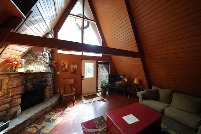 living room with hardwood / wood-style floors, high vaulted ceiling, and a stone fireplace