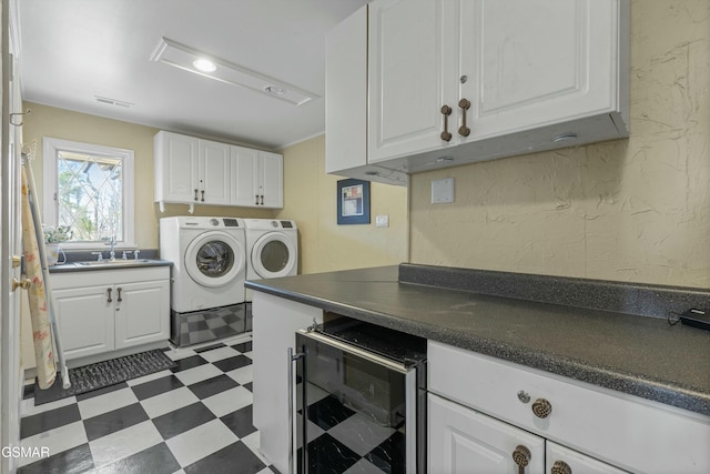 laundry room featuring wine cooler, dark floors, washer and clothes dryer, visible vents, and a sink