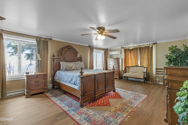 bedroom featuring a baseboard heating unit, light wood-type flooring, a wall mounted air conditioner, and crown molding