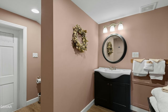 bathroom with baseboards, visible vents, wood finished floors, and vanity