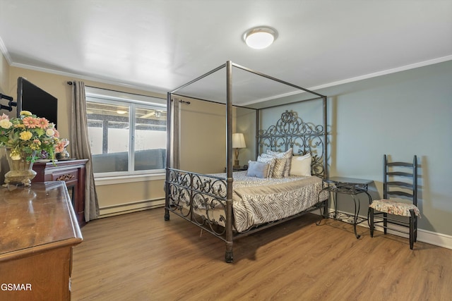 bedroom with ornamental molding, baseboard heating, wood finished floors, and baseboards