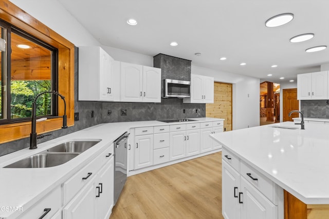 kitchen with light countertops, appliances with stainless steel finishes, a sink, and white cabinetry