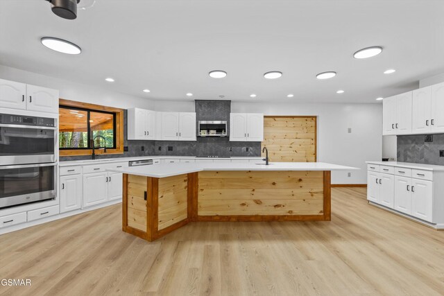 kitchen with white cabinets, appliances with stainless steel finishes, light countertops, and a center island