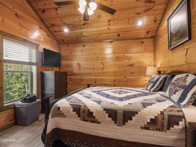 bedroom with vaulted ceiling, ceiling fan, wooden walls, wooden ceiling, and light hardwood / wood-style floors