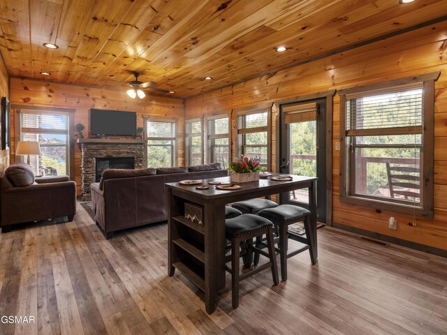 dining room featuring hardwood / wood-style floors, ceiling fan, wooden walls, and wood ceiling