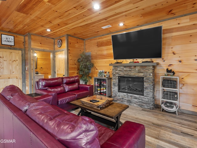 living room featuring wood-type flooring, wooden walls, a stone fireplace, and wooden ceiling