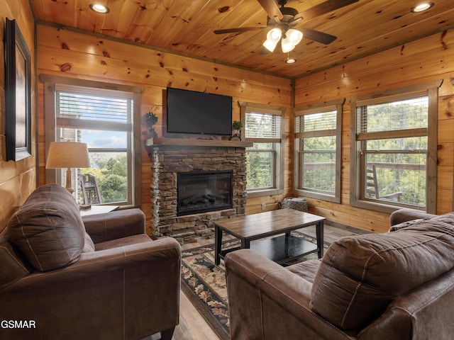 living room with light wood-type flooring, wood ceiling, ceiling fan, a fireplace, and wood walls