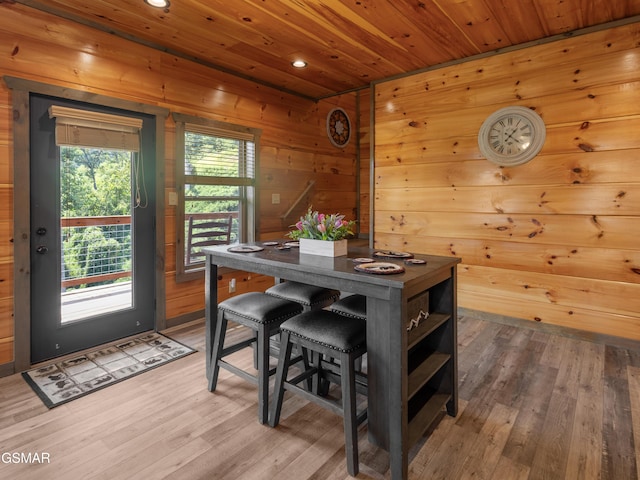 dining area with wood ceiling, a healthy amount of sunlight, wood-type flooring, and wooden walls