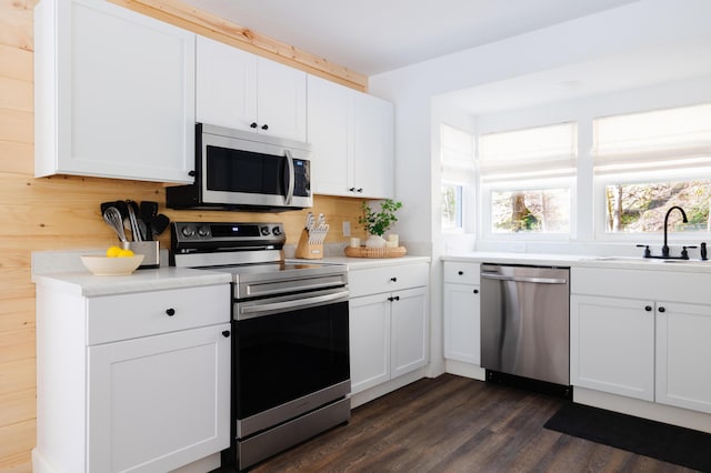 kitchen featuring stainless steel appliances, light countertops, dark wood-type flooring, white cabinetry, and a sink