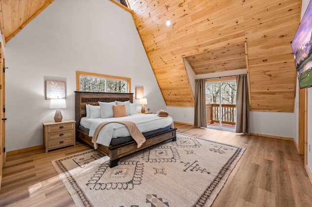 bedroom featuring access to exterior, light wood-style flooring, baseboards, and high vaulted ceiling