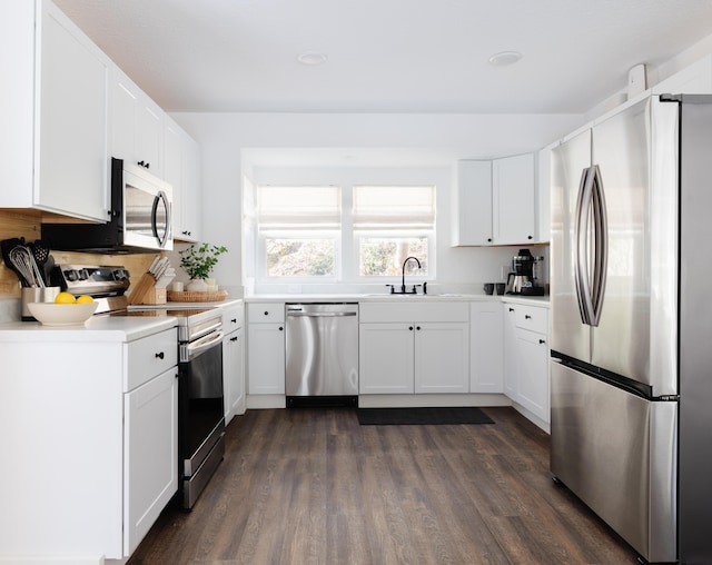 kitchen featuring dark wood-style floors, stainless steel appliances, light countertops, white cabinetry, and a sink