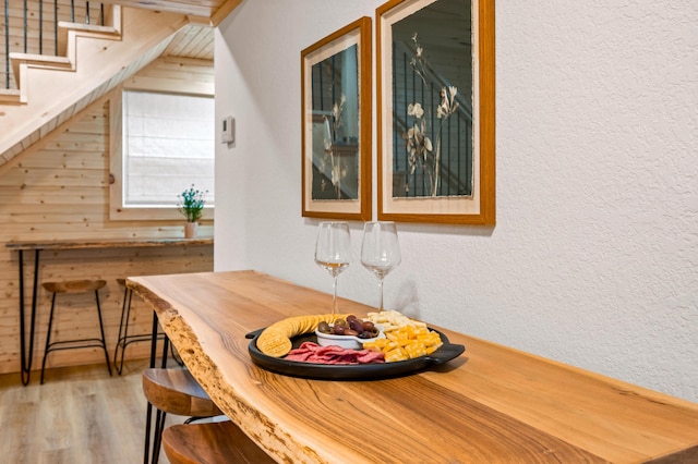 dining space featuring a textured wall, stairway, and wood finished floors