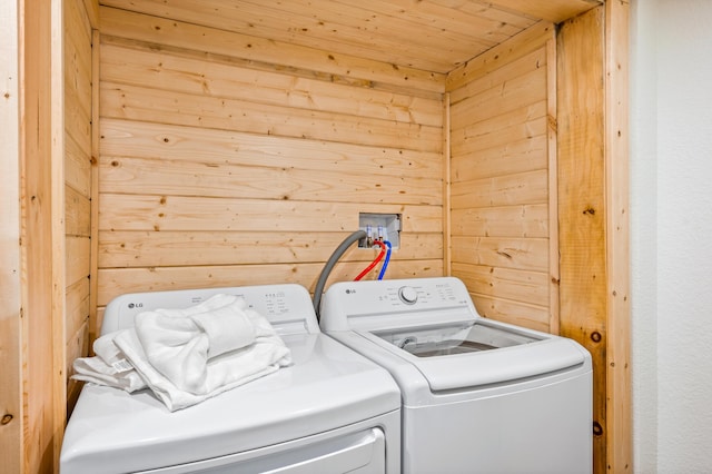 laundry room featuring laundry area, wood walls, wooden ceiling, and washing machine and dryer