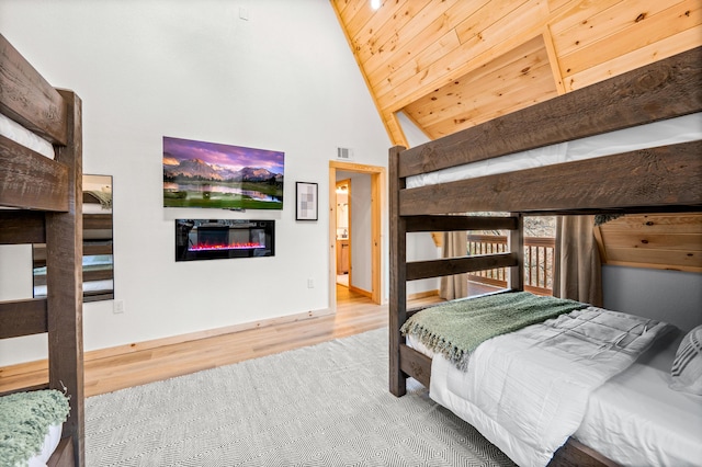 bedroom with high vaulted ceiling, wood finished floors, wood ceiling, visible vents, and a glass covered fireplace