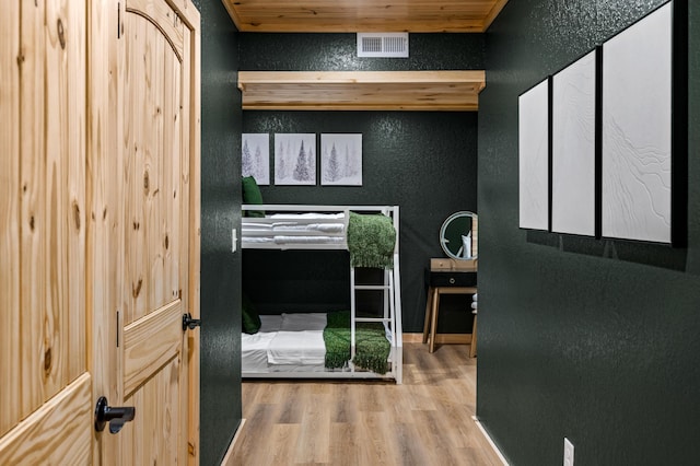 interior space with visible vents, a textured wall, and wood finished floors