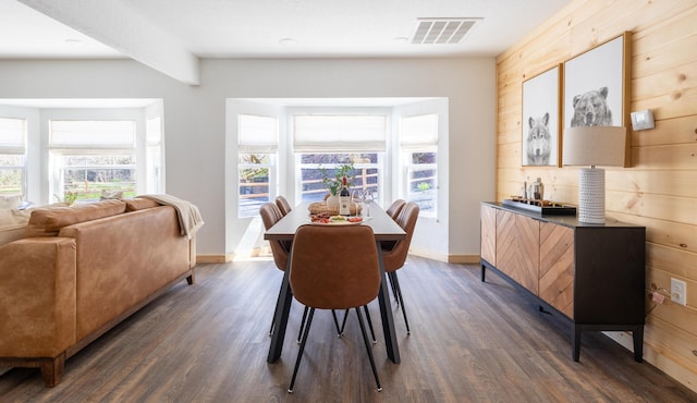 dining room featuring wood walls, visible vents, and dark wood-style flooring