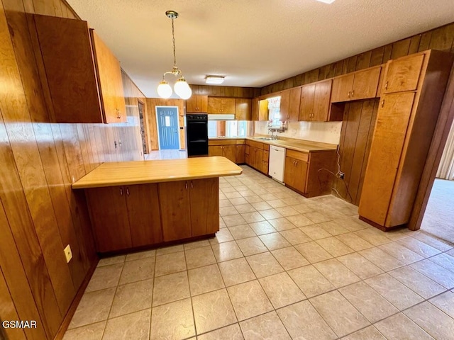 kitchen featuring kitchen peninsula, white dishwasher, and wooden walls