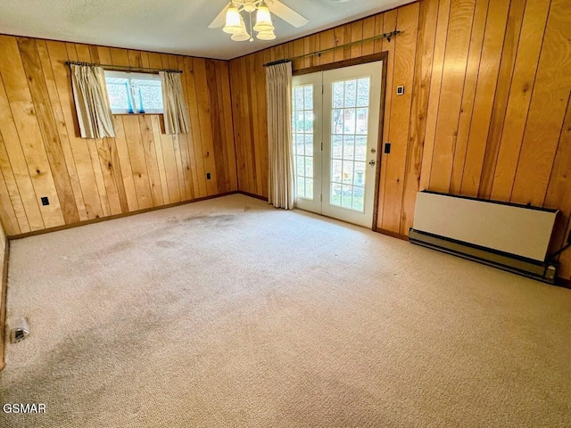 carpeted empty room with wooden walls, ceiling fan, and a healthy amount of sunlight