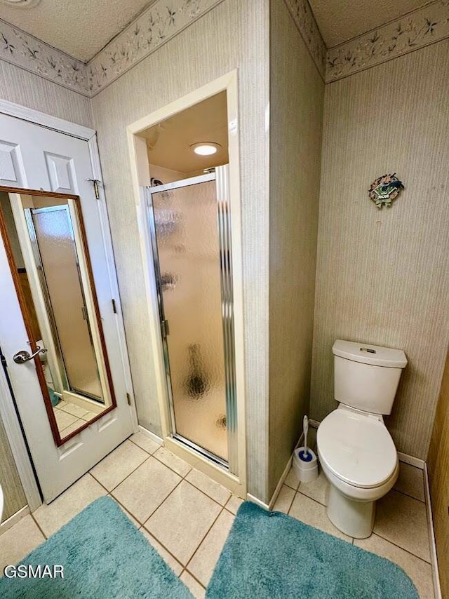 bathroom featuring toilet, tile patterned floors, and an enclosed shower