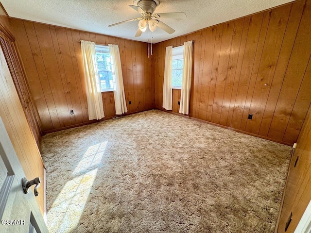 unfurnished room featuring carpet flooring, plenty of natural light, and wooden walls