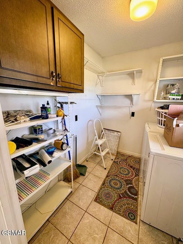 washroom with washing machine and dryer, light tile patterned floors, cabinets, and a textured ceiling