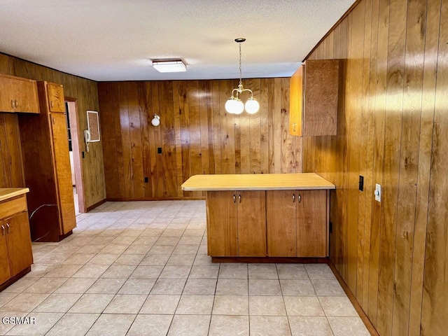 kitchen with pendant lighting, a textured ceiling, wooden walls, and an inviting chandelier