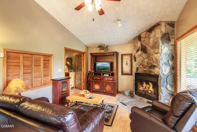 living room featuring vaulted ceiling, a fireplace, a textured ceiling, and wood finished floors