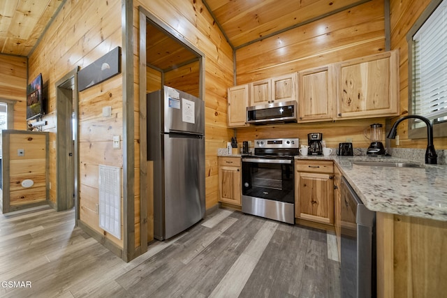 kitchen with wooden walls, visible vents, appliances with stainless steel finishes, light brown cabinets, and a sink