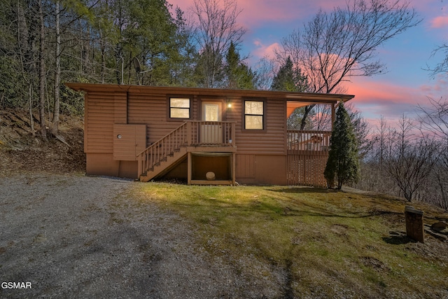 back of property featuring faux log siding, a lawn, driveway, and stairs