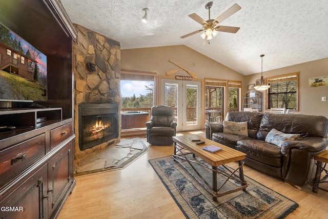 living area with lofted ceiling, a healthy amount of sunlight, a textured ceiling, and light wood finished floors