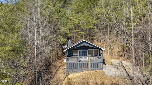 view of front of property featuring a chimney and a wooded view