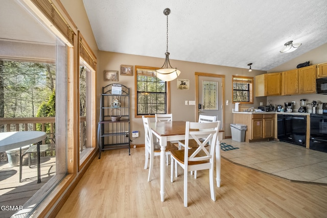 dining area featuring lofted ceiling, light wood-type flooring, baseboards, and a textured ceiling