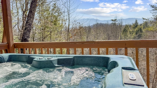 deck featuring a mountain view, a hot tub, and a wooded view