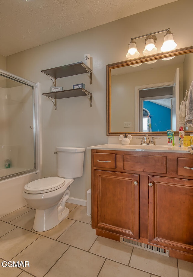 full bathroom featuring a textured ceiling, tile patterned flooring, vanity, and enclosed tub / shower combo