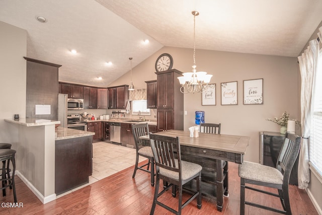 dining area with light wood-type flooring, lofted ceiling, sink, and a chandelier