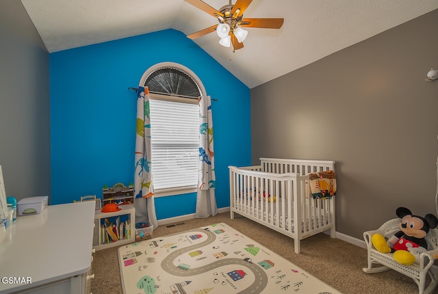 bedroom with lofted ceiling, a nursery area, a textured ceiling, carpet, and ceiling fan