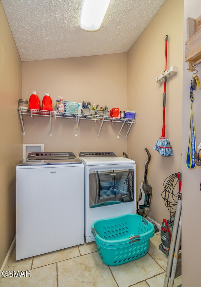 laundry area with independent washer and dryer, light tile patterned floors, and a textured ceiling