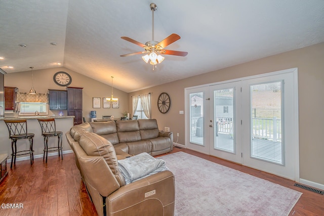 living room featuring dark wood-type flooring, lofted ceiling, and ceiling fan with notable chandelier