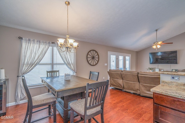 dining space with hardwood / wood-style flooring, vaulted ceiling, and a notable chandelier