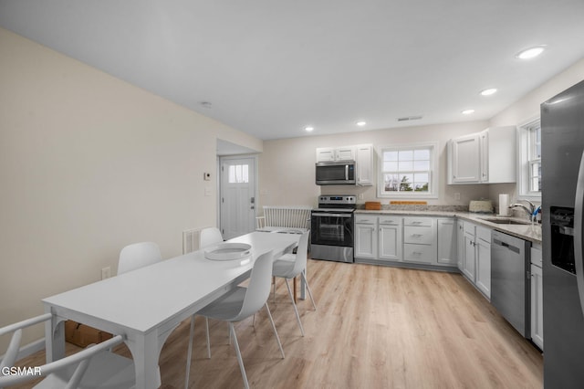 kitchen with white cabinetry, stainless steel appliances, light hardwood / wood-style flooring, and sink