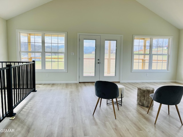 living area with light wood-type flooring, lofted ceiling, and french doors