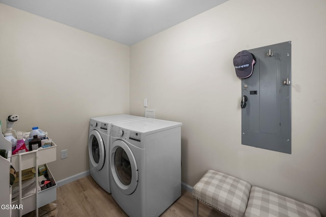 clothes washing area featuring electric panel, washer and dryer, and light wood-type flooring