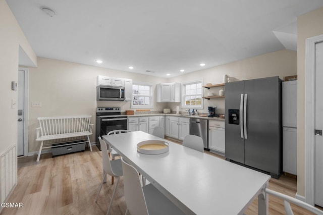 kitchen with light hardwood / wood-style floors, appliances with stainless steel finishes, white cabinetry, and sink