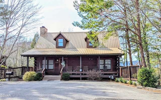 log cabin with covered porch, log exterior, metal roof, and a chimney