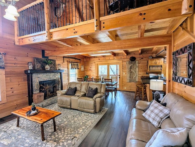 living room featuring wooden walls, a fireplace with raised hearth, wooden ceiling, beamed ceiling, and wood finished floors