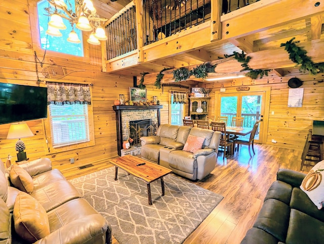 living room featuring hardwood / wood-style flooring, a healthy amount of sunlight, wood walls, and a high ceiling