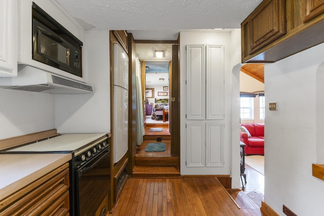 kitchen featuring black appliances, a textured ceiling, and light wood-type flooring