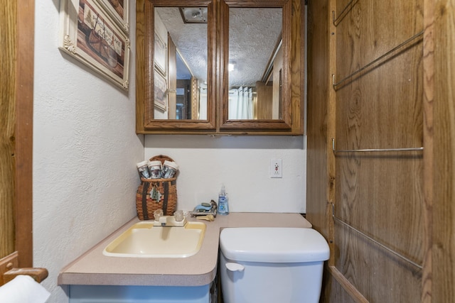 bathroom with toilet, sink, and a textured ceiling