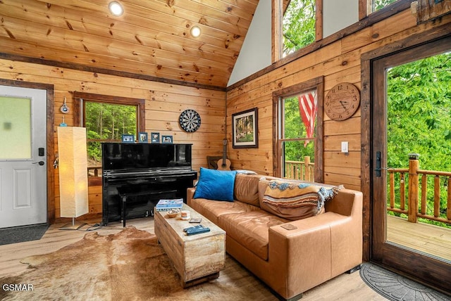 living room with vaulted ceiling, plenty of natural light, wood walls, wooden ceiling, and wood finished floors