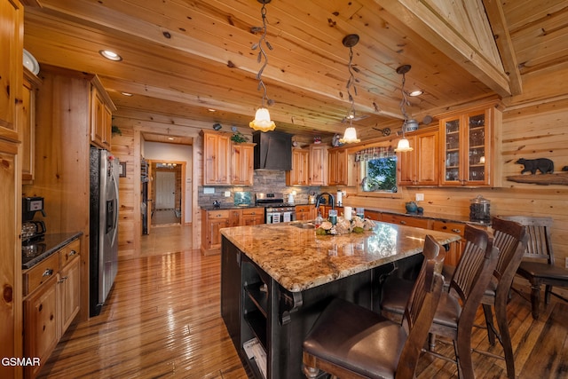 3995 Island View Way, Sevierville, TN 37876 - kitchen featuring appliances with stainless steel finishes, wall chimney exhaust hood, a center island with sink, open shelves, and wooden walls